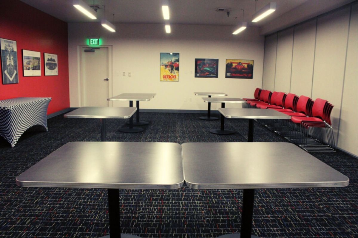 A room with tables and chairs and an exit sign on the wall