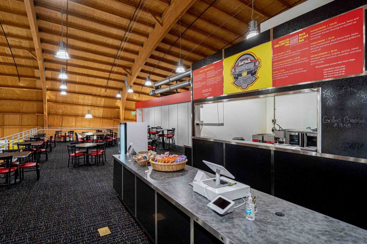 The inside of a restaurant with tables and chairs and a counter.