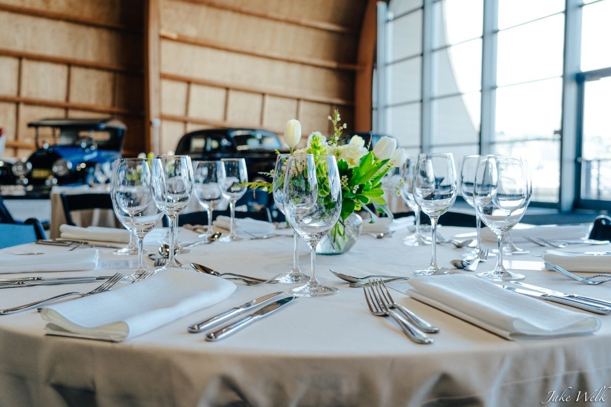 A table set for a wedding reception with a vase of flowers on it.