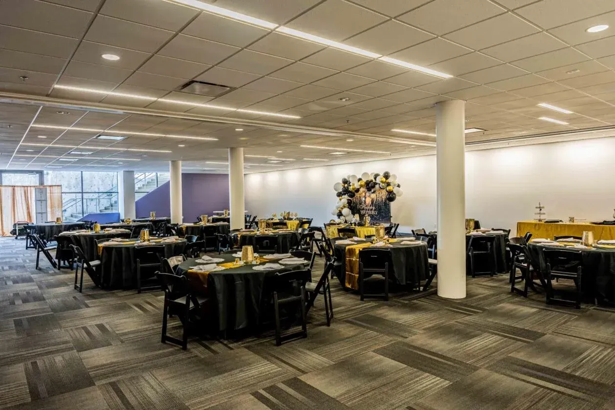 A large room with tables and chairs set up for a party.