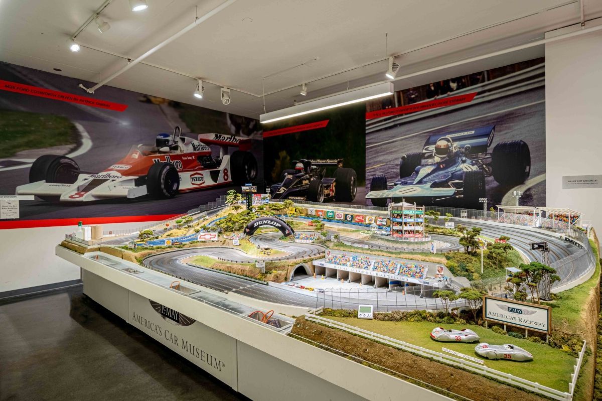 A model of a race track with a picture of a race car on the wall.