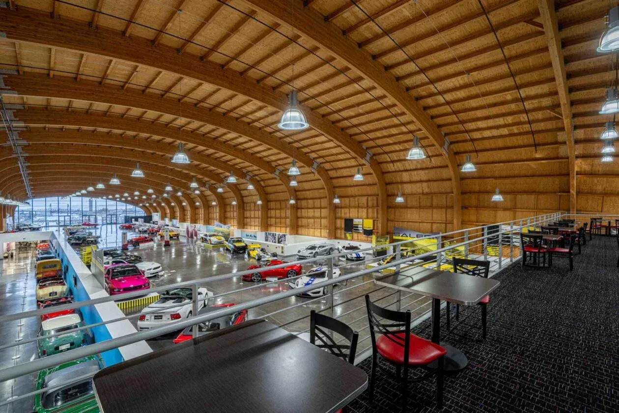 A large warehouse filled with cars and tables and chairs.