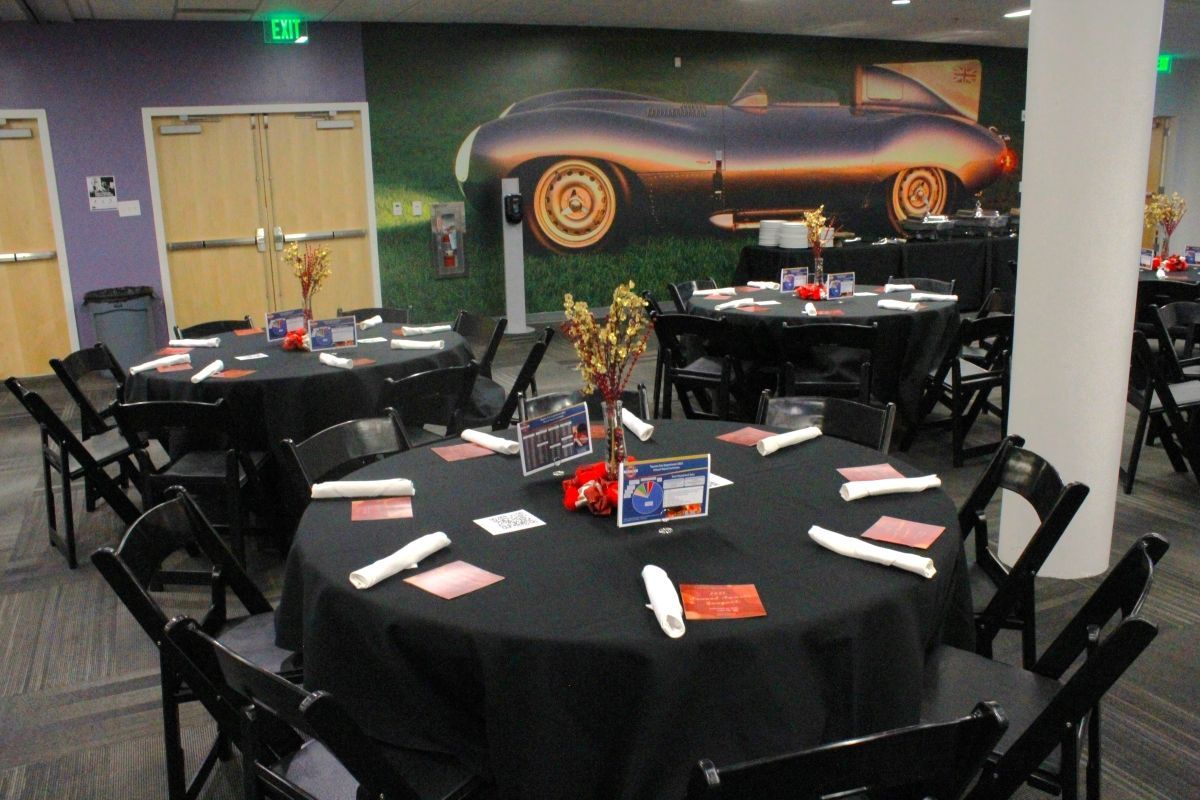 A room with tables and chairs and a picture of a car on the wall