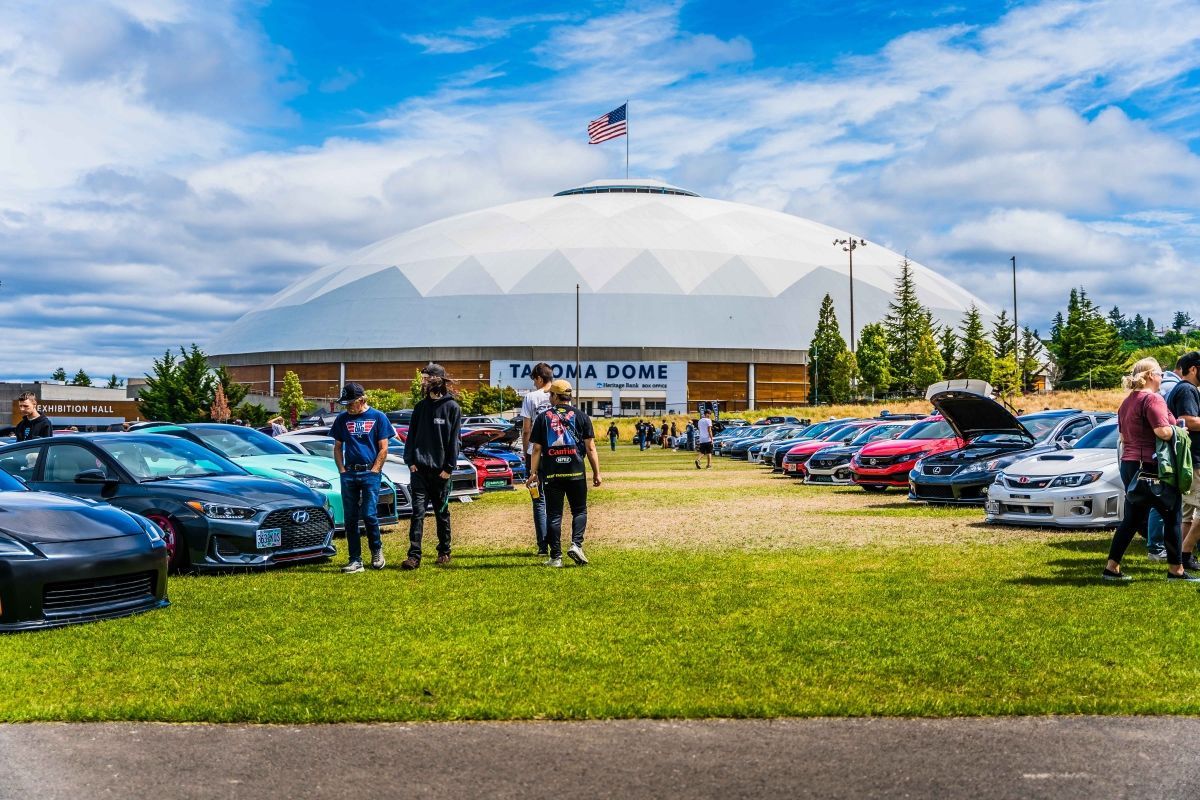 A group of people are standing in front of a dome in a parking lot.
