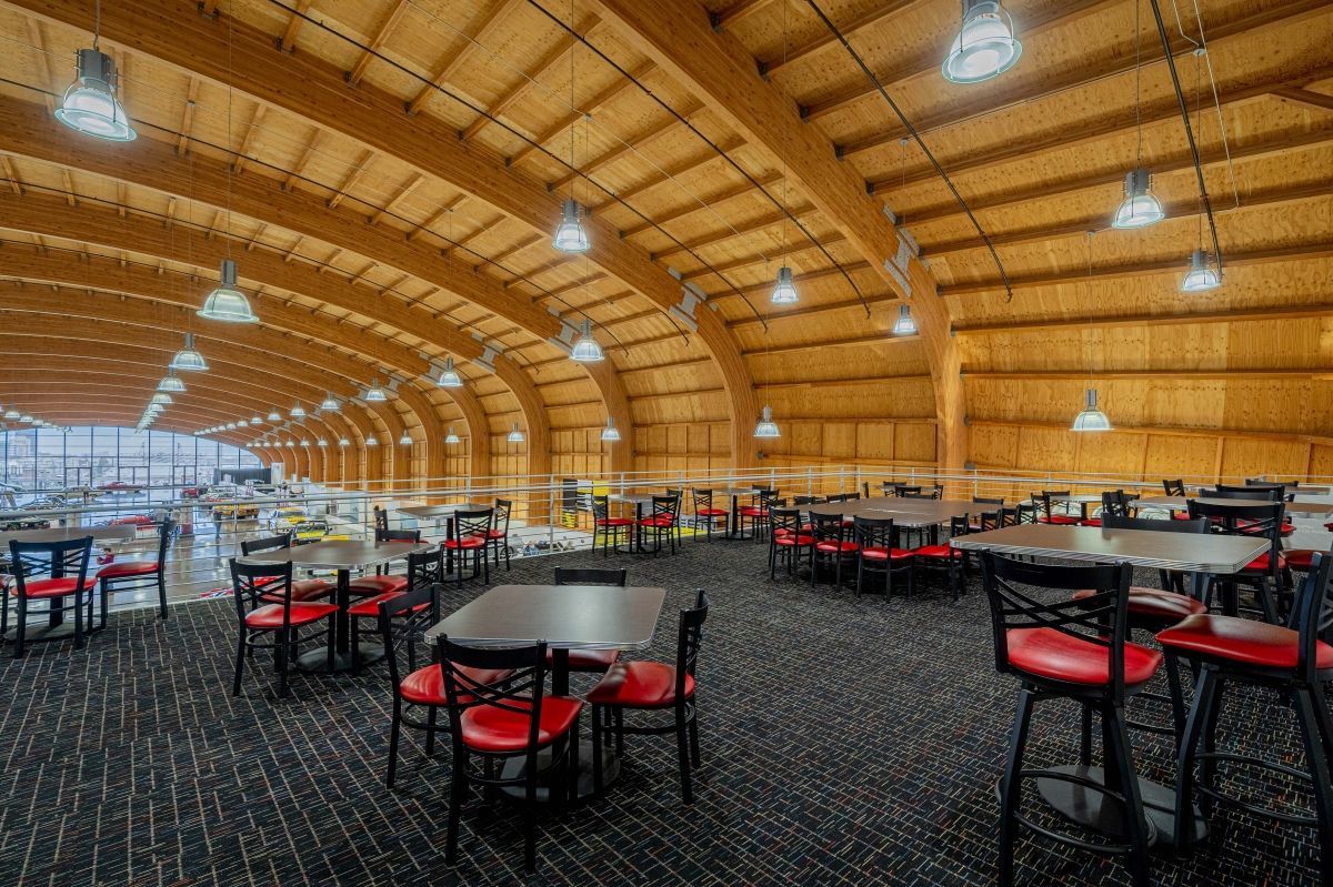 A large dining room with tables and chairs under a wooden ceiling.