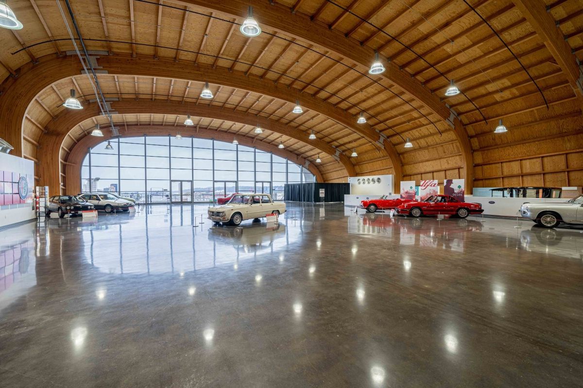A large room with cars parked in it and a wooden ceiling.