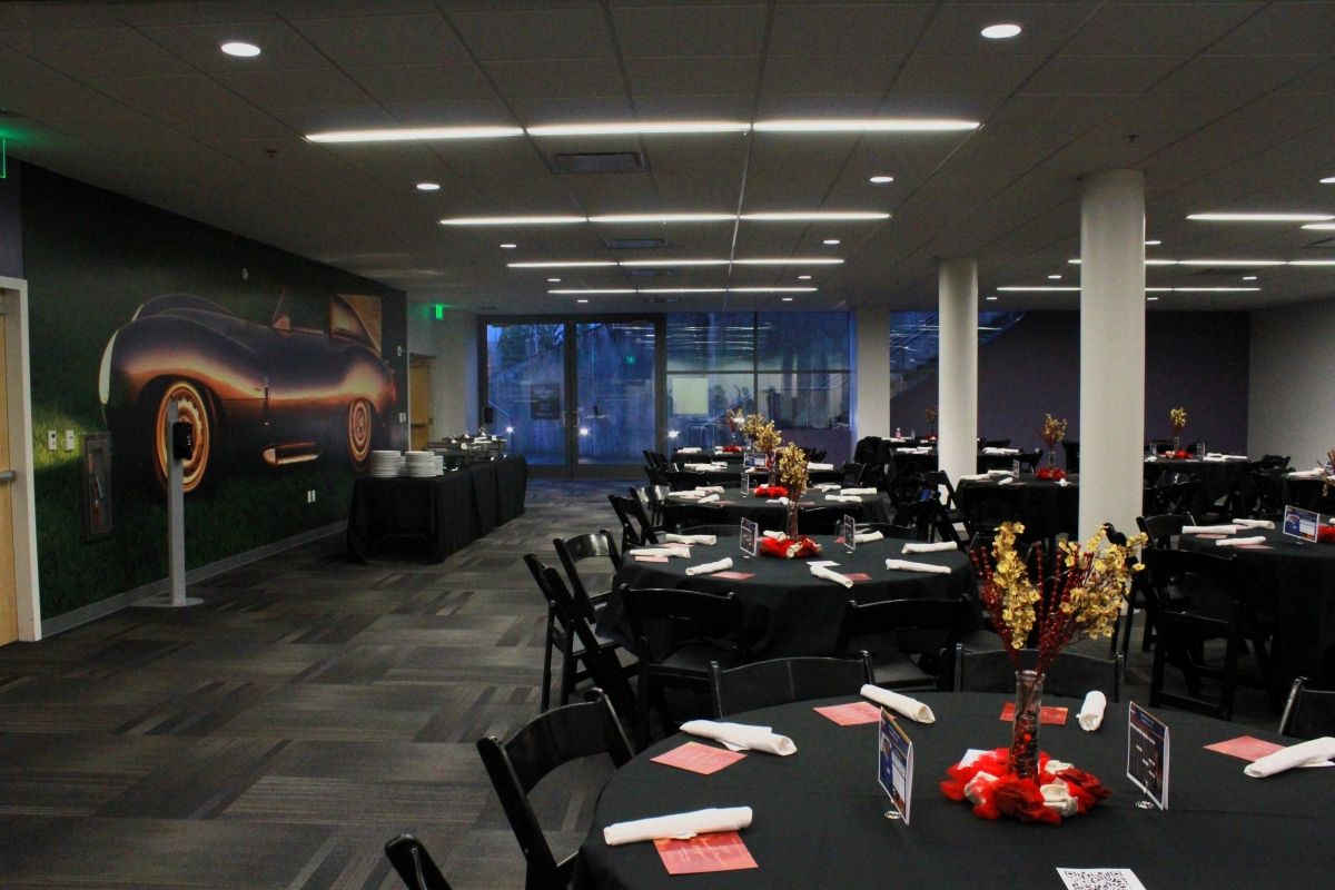 A large room with tables and chairs and a car on the wall