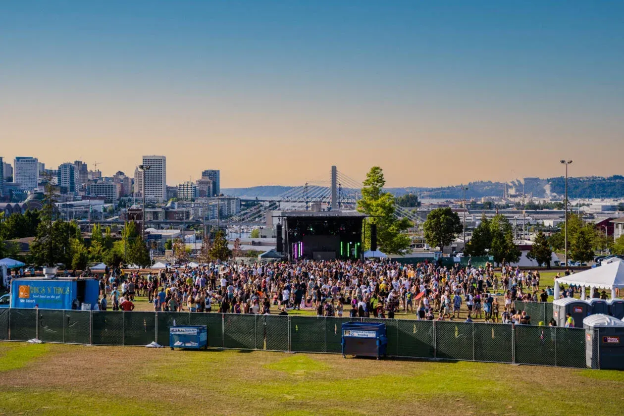 A large crowd of people are gathered in front of a stage at a music festival.