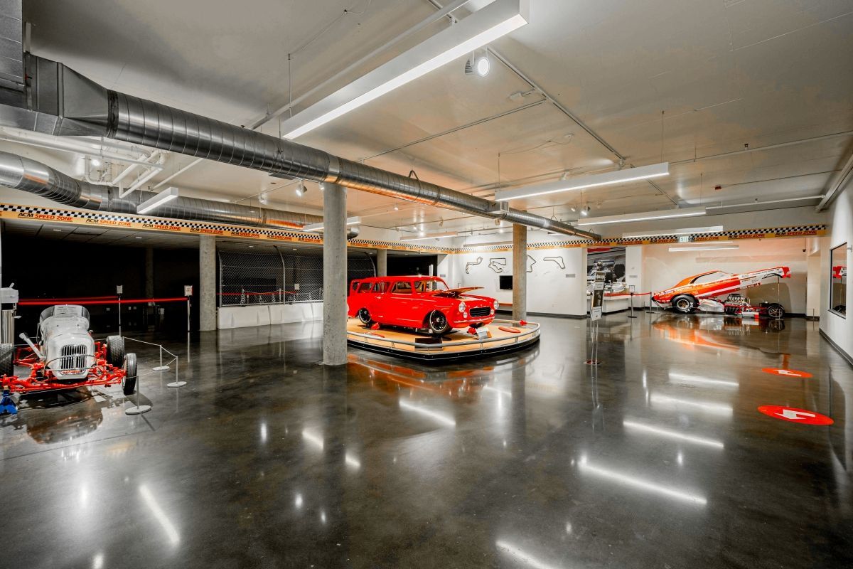 A red car is parked in a garage with other cars.
