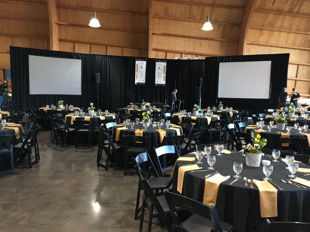 A large room filled with tables and chairs and projector screens.