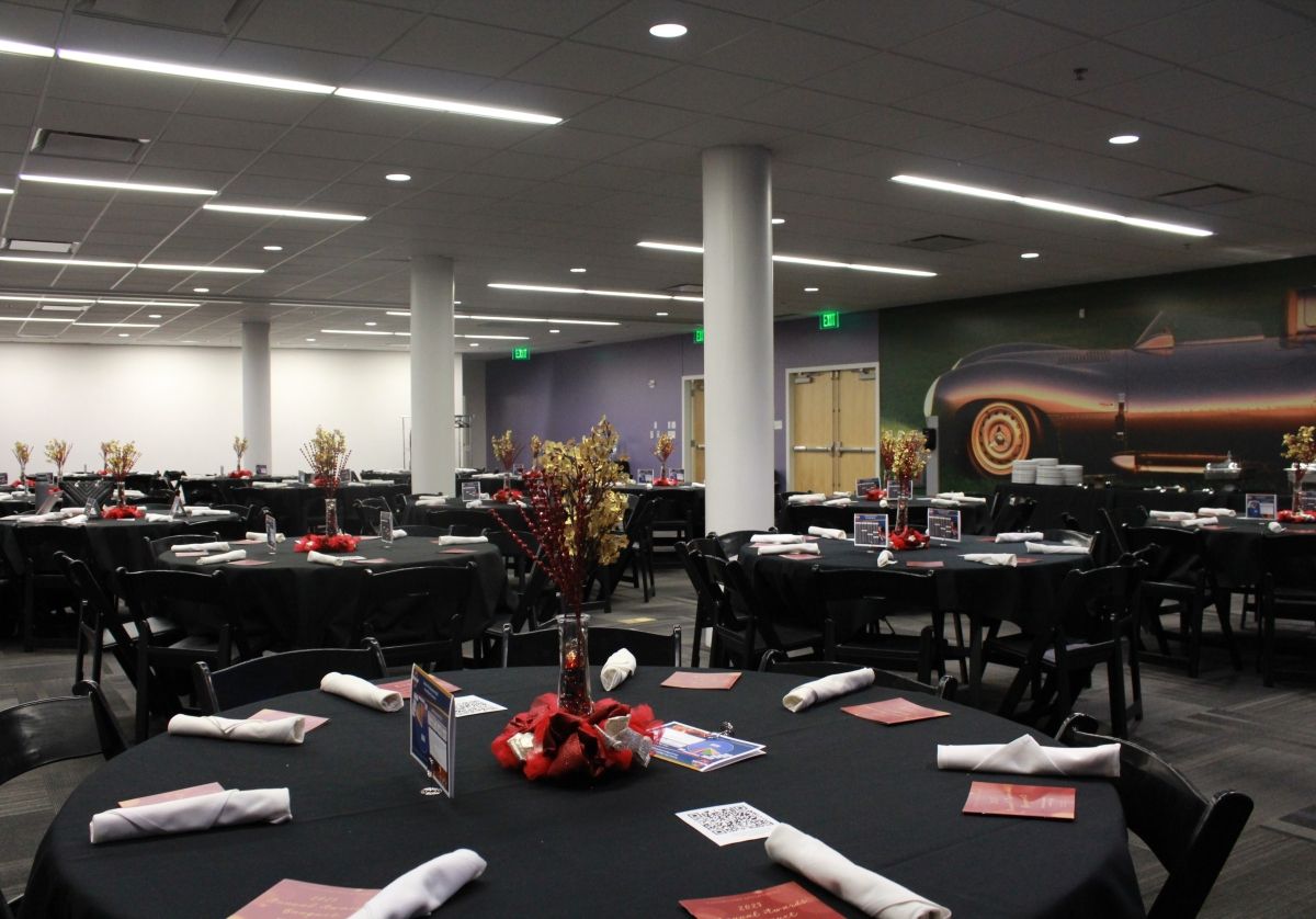 A large room with tables and chairs and a picture of a car on the wall