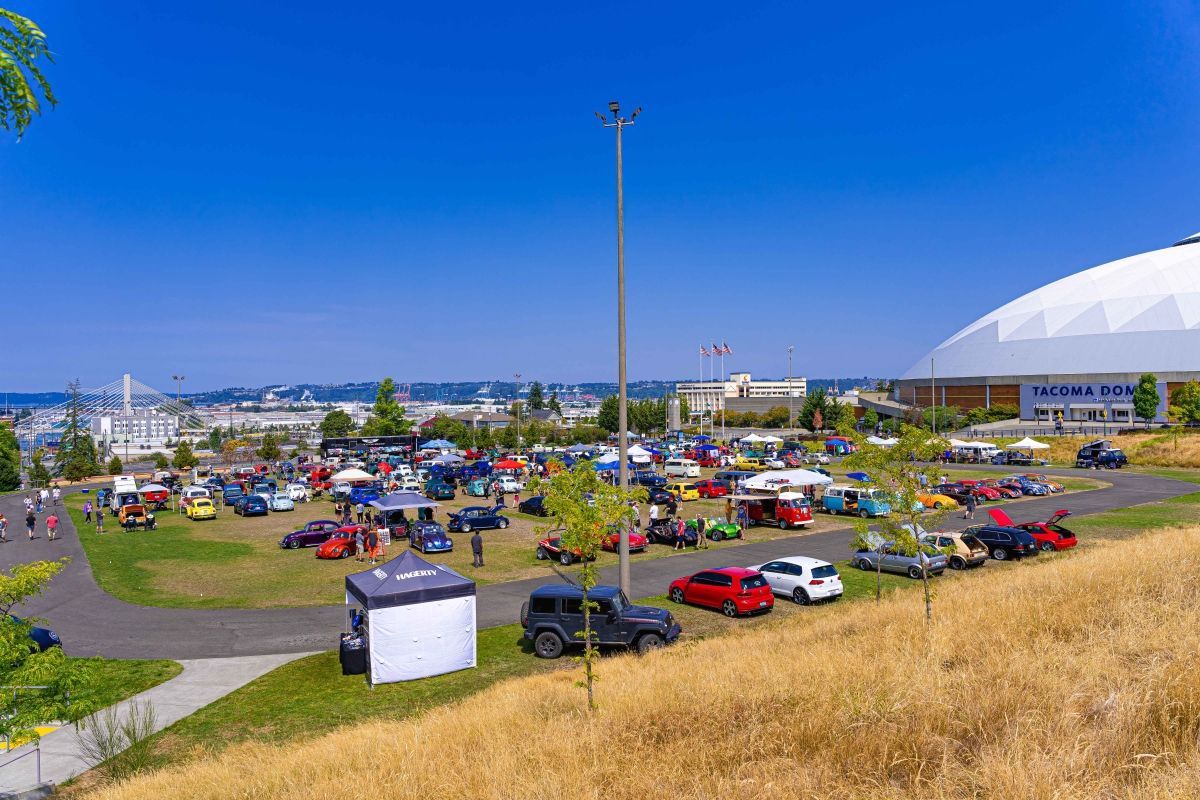 A lot of cars are parked in a parking lot at a car show.
