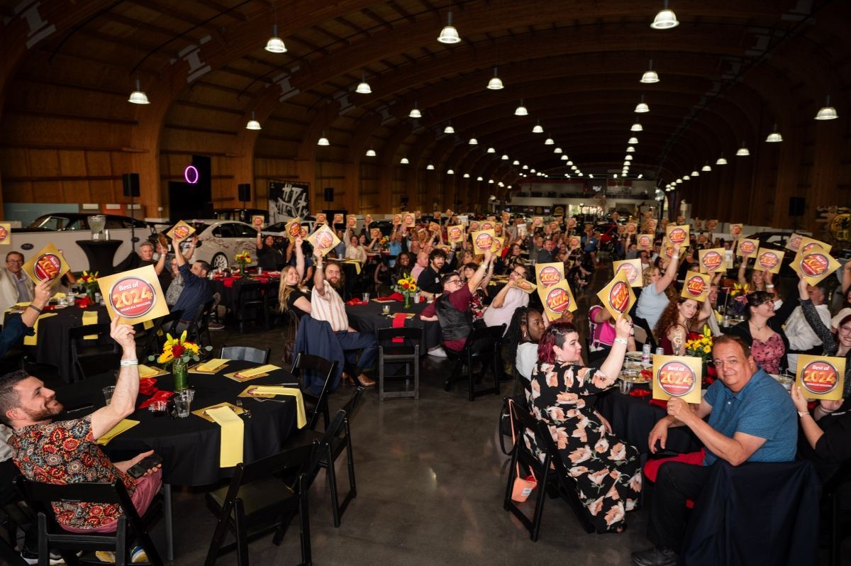 A large group of people are sitting at tables holding up signs.