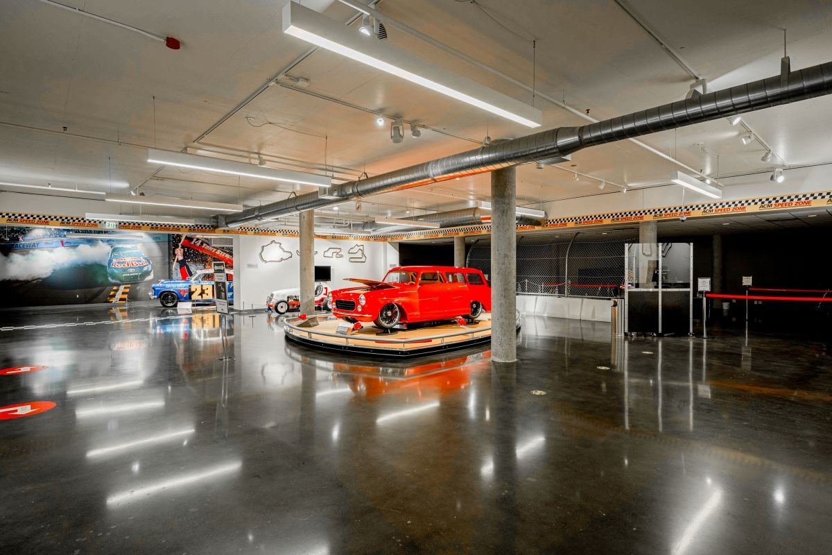 A red car is on display in a large room.
