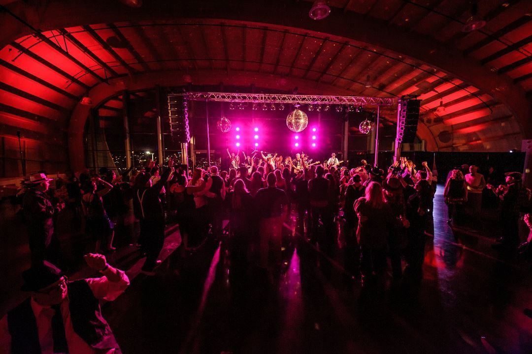 A crowd of people are dancing in front of a stage at a concert.