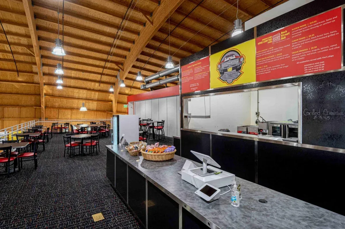 The inside of a restaurant with tables and chairs and a counter.