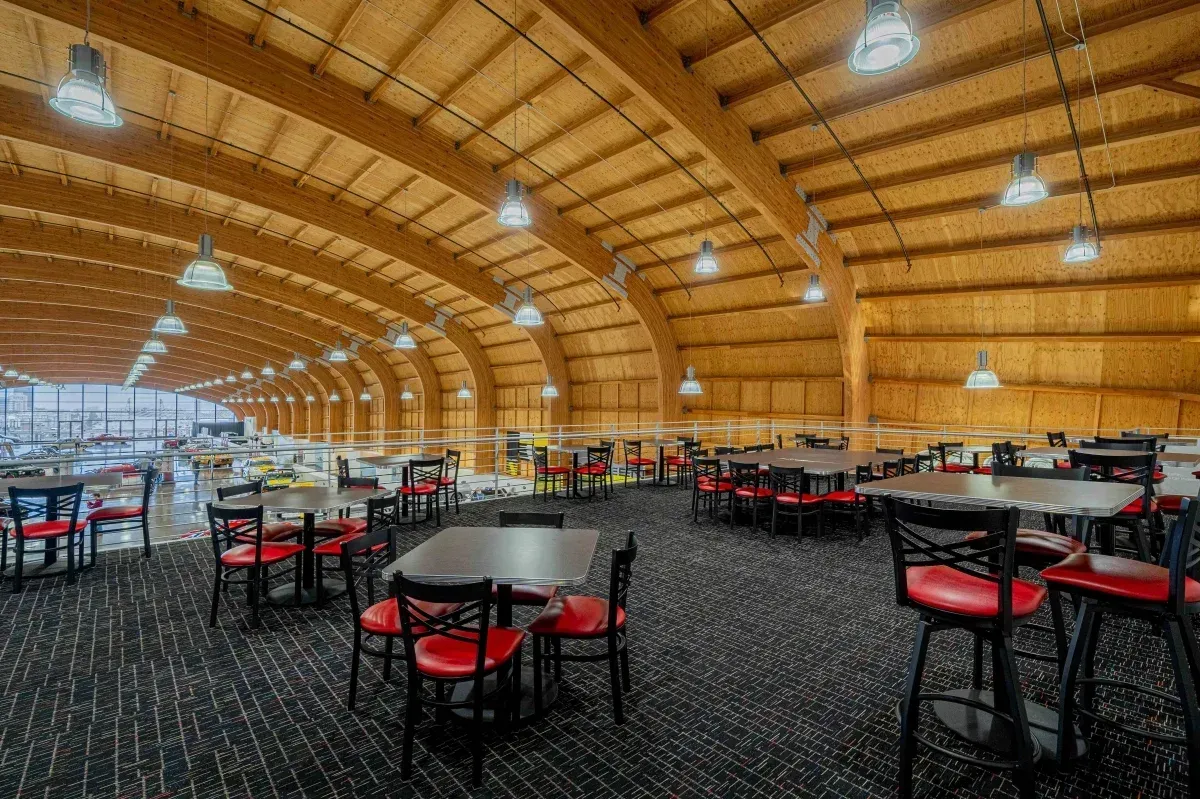 A large dining room with tables and chairs under a wooden ceiling.