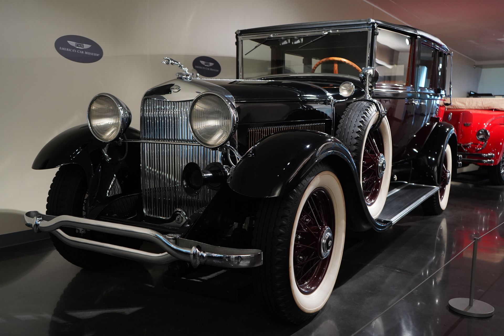 A black car with white tires is parked in a museum