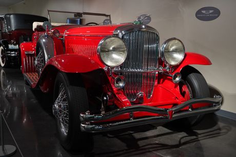 An old red car is parked in a museum.