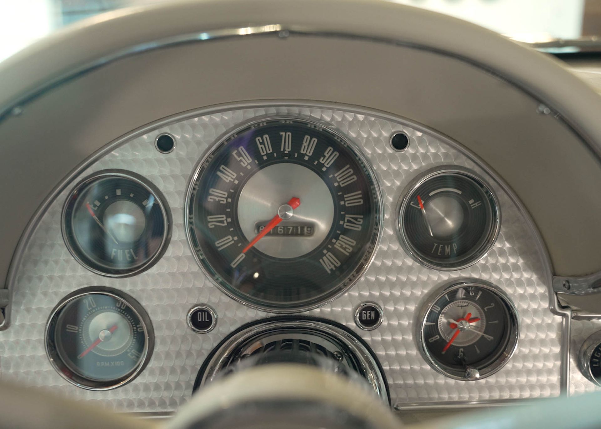 A close up of a car dashboard with a speedometer and a clock.