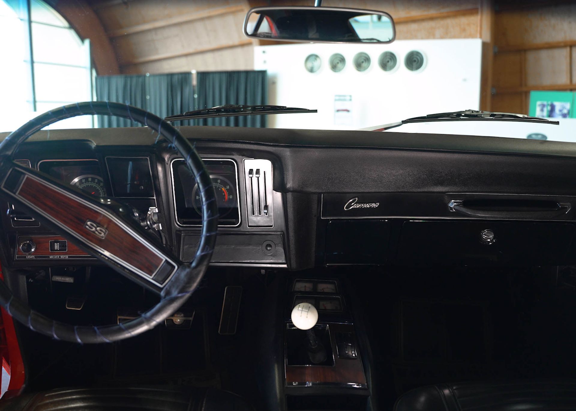 A car dashboard with a steering wheel and a rear view mirror