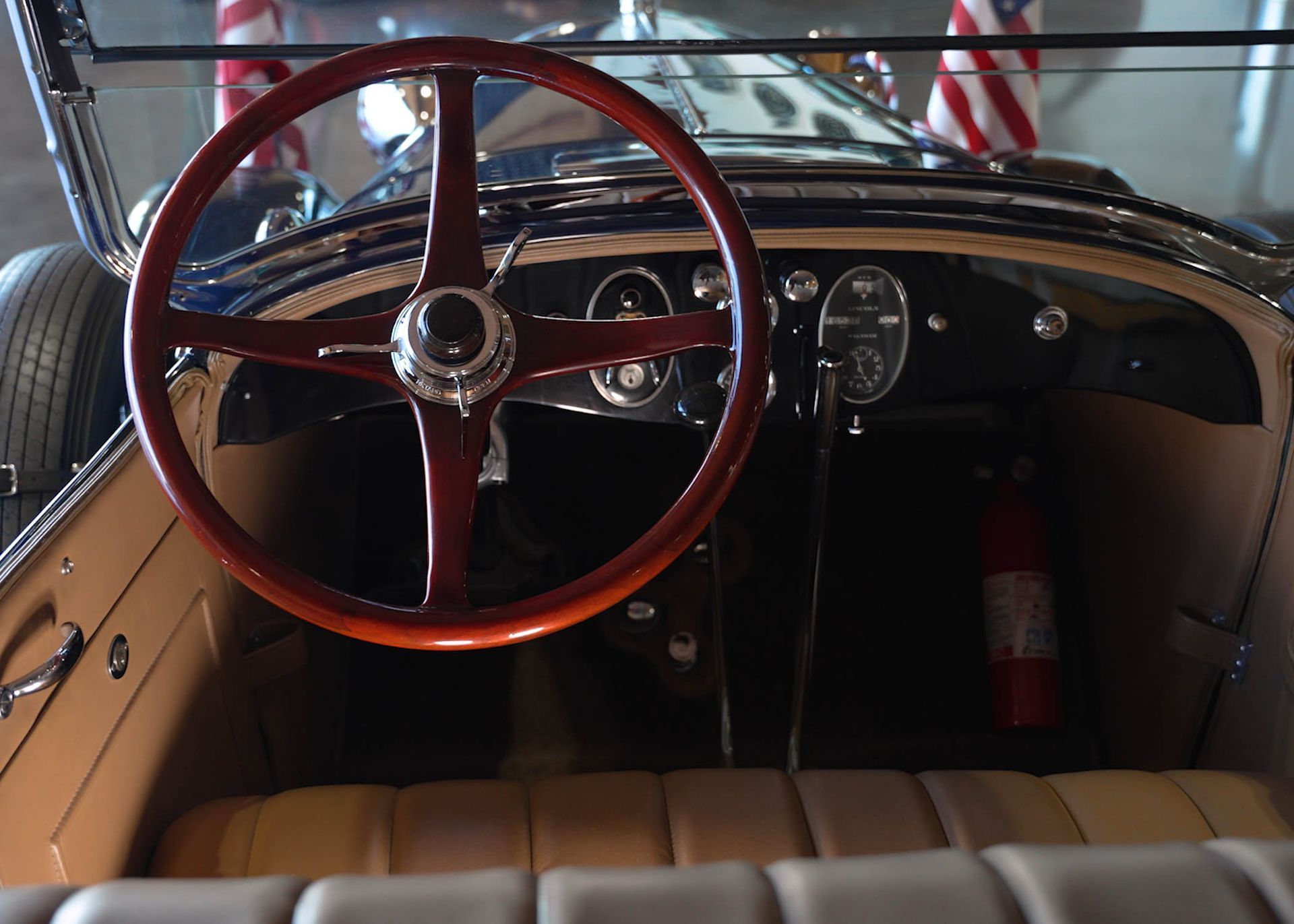 The inside of an old car with a wooden steering wheel