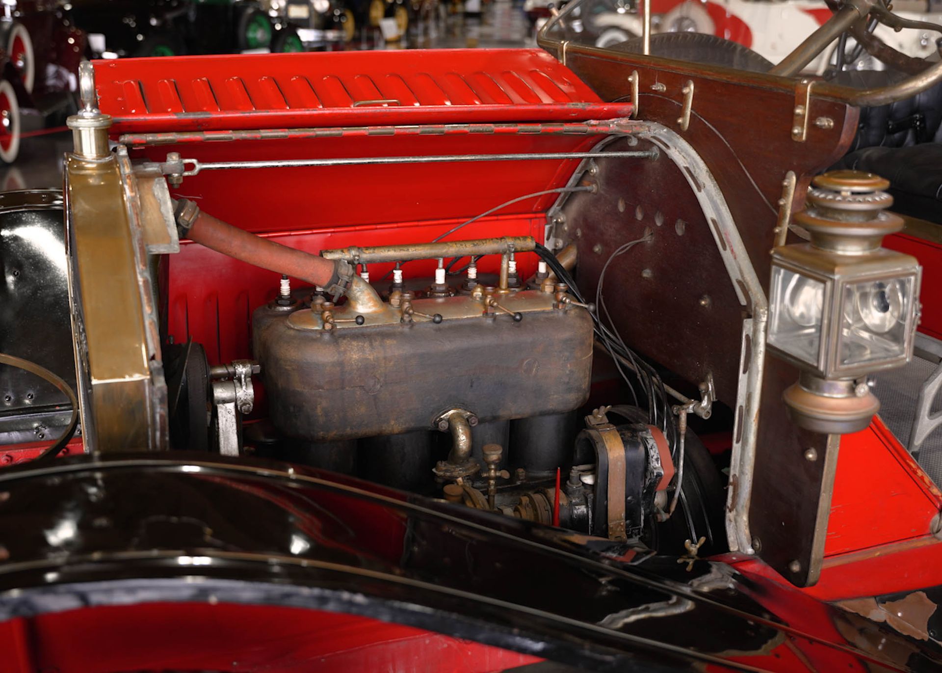 A close up of an old car engine with a red hood