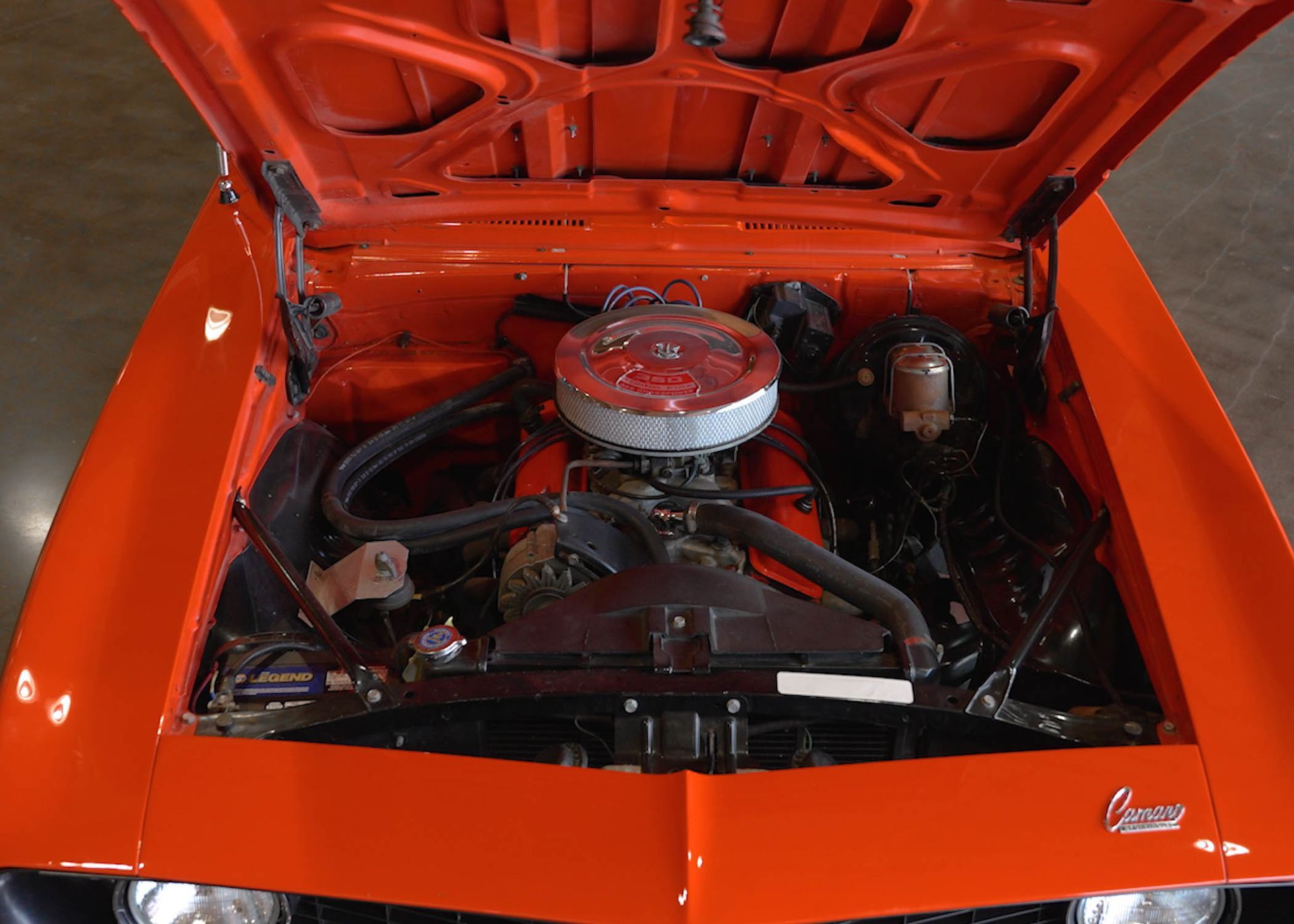 The engine of an orange car with the hood open