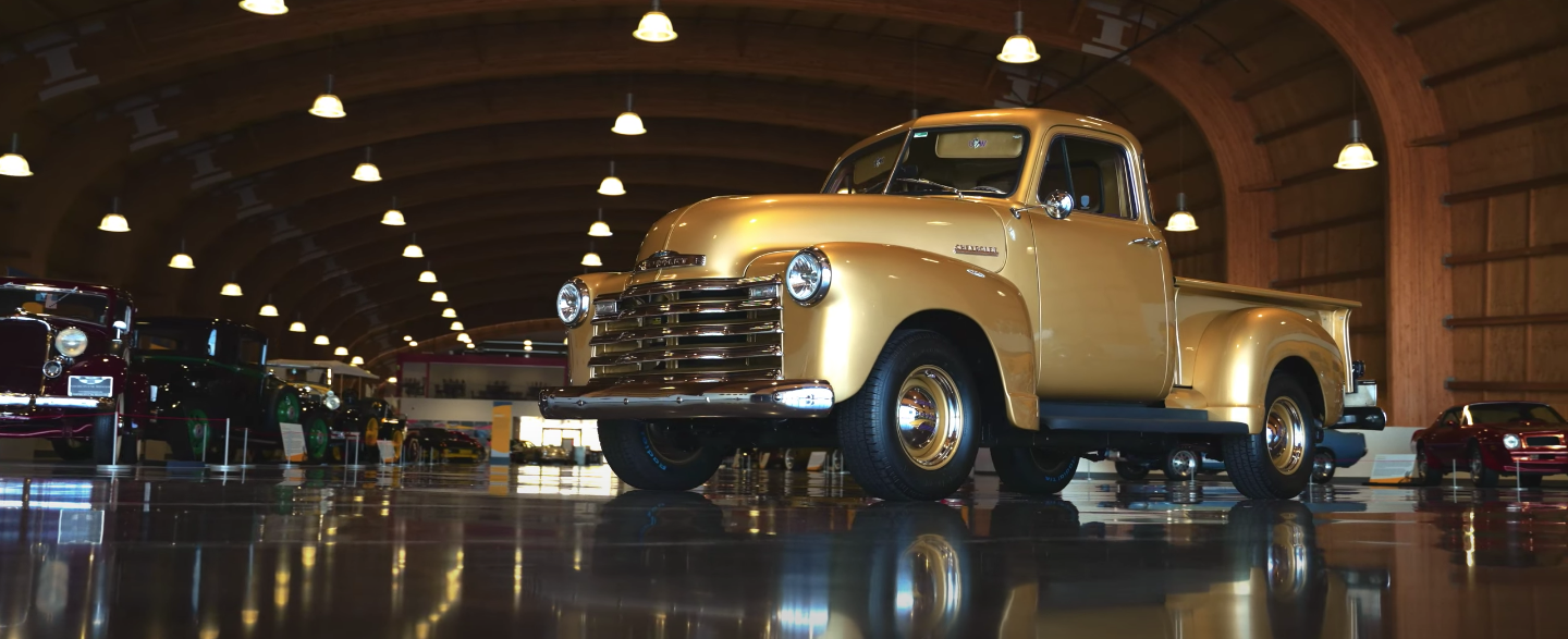 An old gold truck is parked in a garage.