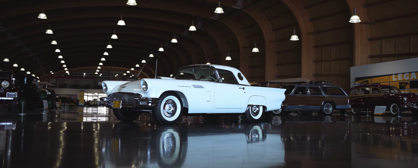 A white car is parked in a garage with other cars.
