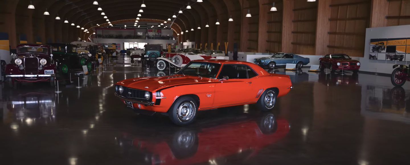 A red car is parked in a garage with other cars.