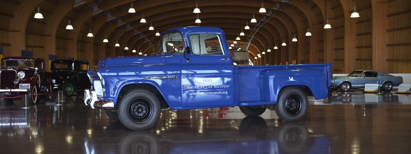 A blue truck is parked in a large warehouse.