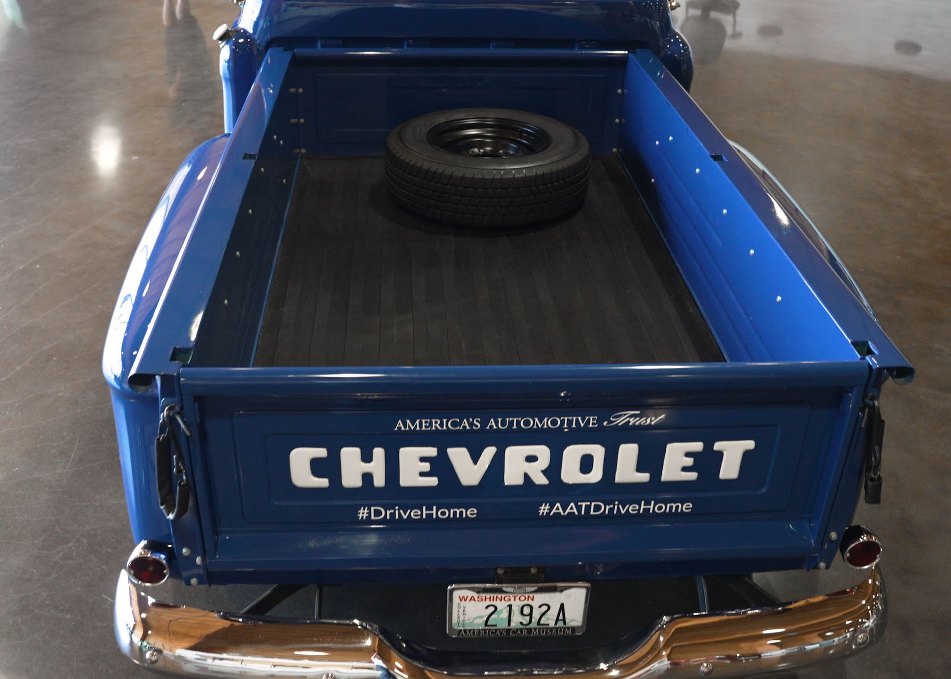 A blue chevrolet truck with a spare tire in the bed