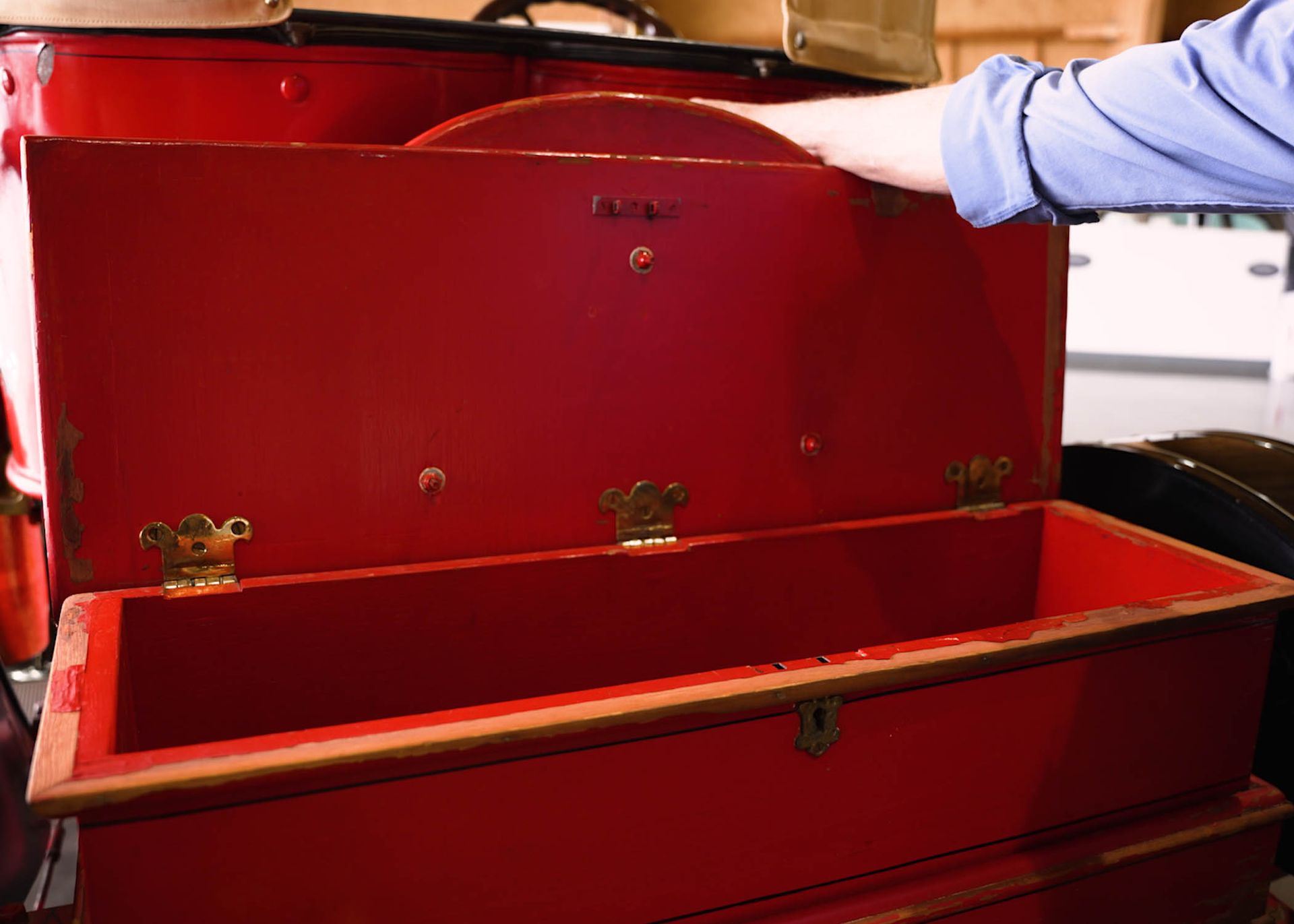 A person is opening a red trunk with the lid open.
