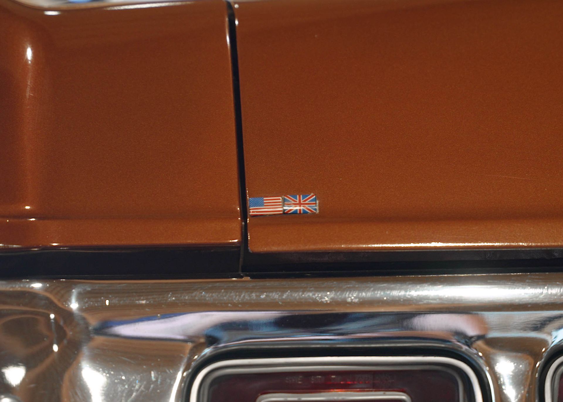 A close up of a brown car with an american flag sticker on it