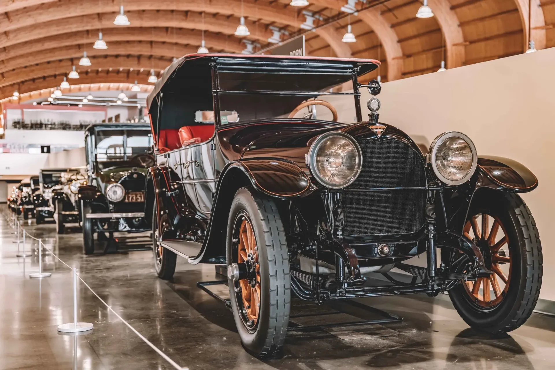 A row of old cars are parked in a garage.