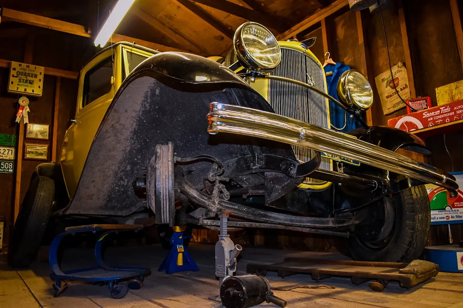 An old car is being worked on in a garage.