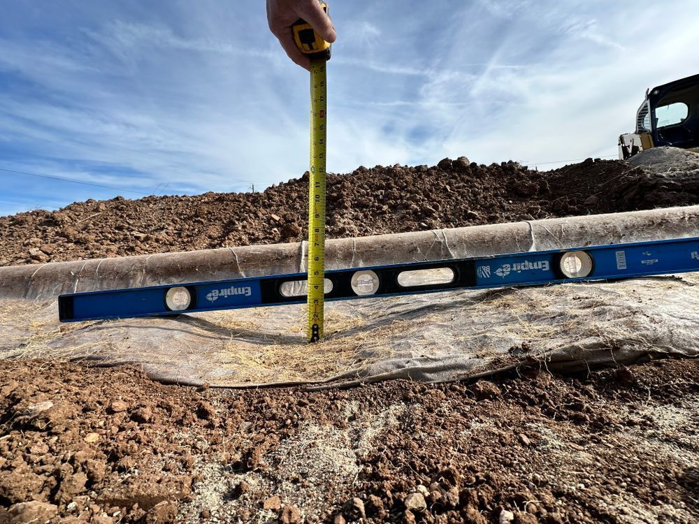 A person measures the height of a curb with a tape measure and level at a construction site.