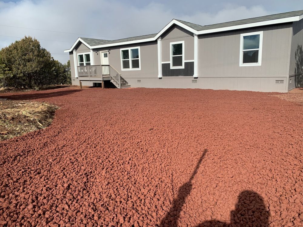 Gray house with red gravel driveway.