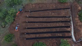 Overhead view of an excavated garden plot with dark rows and two small orange tractors.