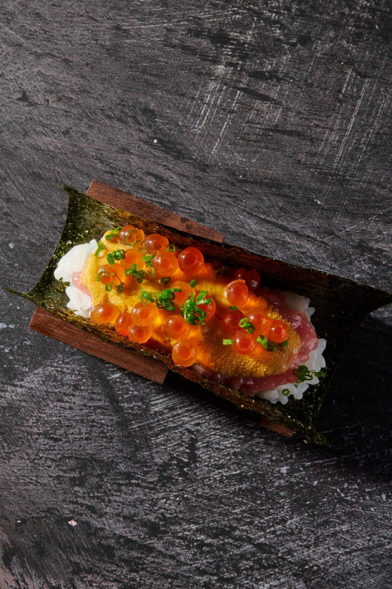 a close up of a sushi roll on a black surface .