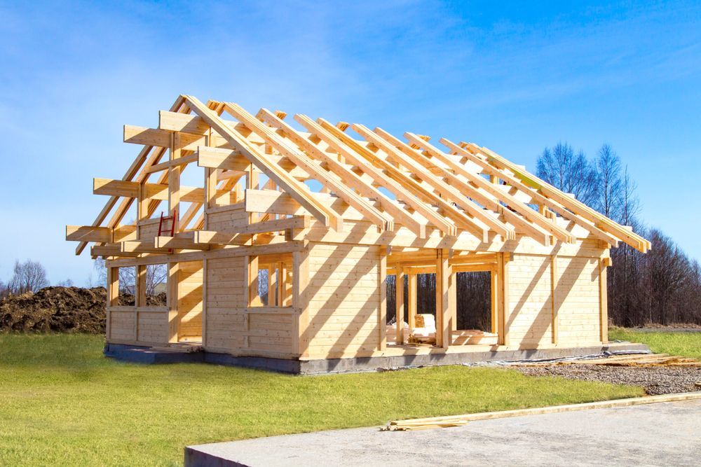 A wooden house is being built on a lush green field.