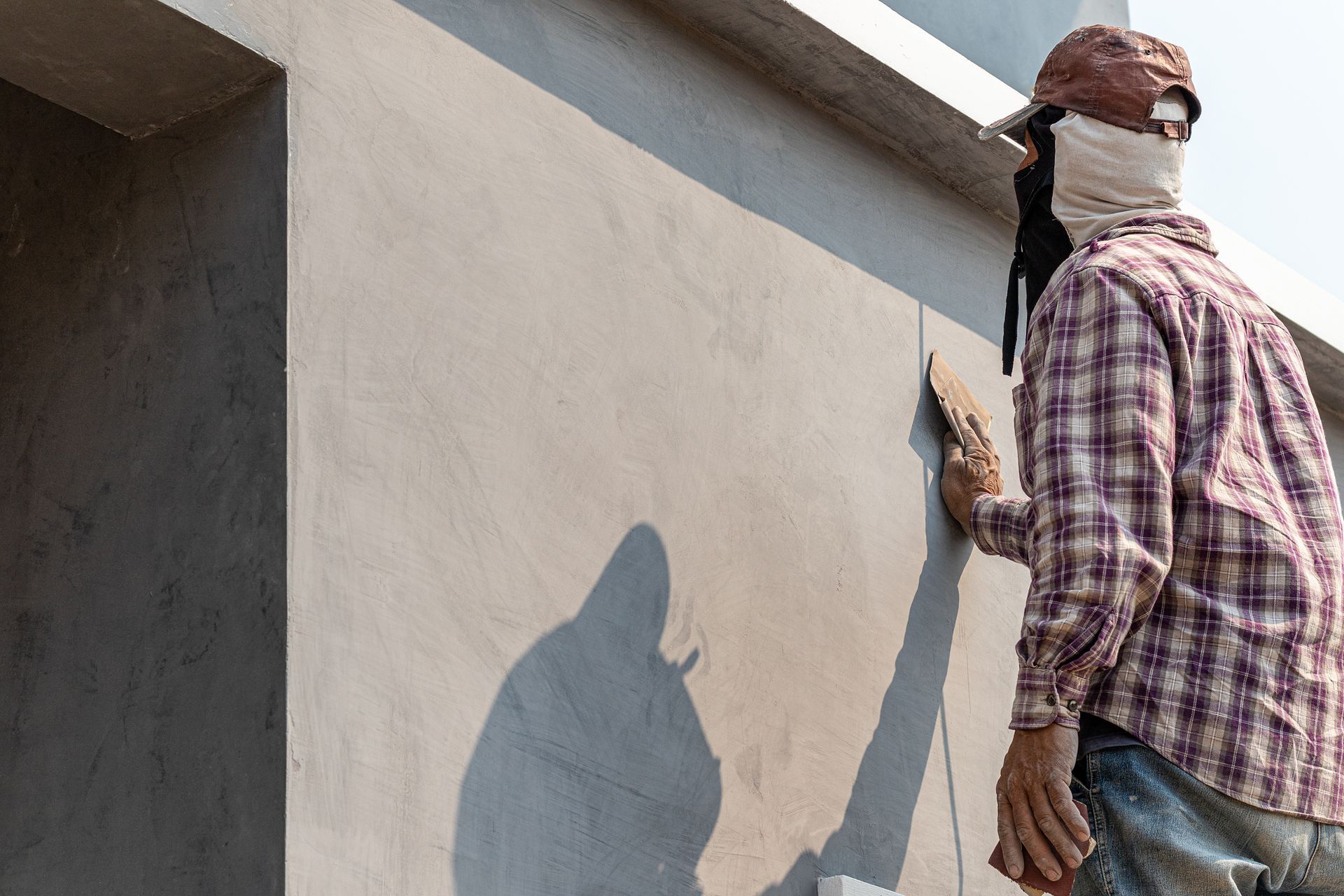 A man is plastering a wall with a spatula.