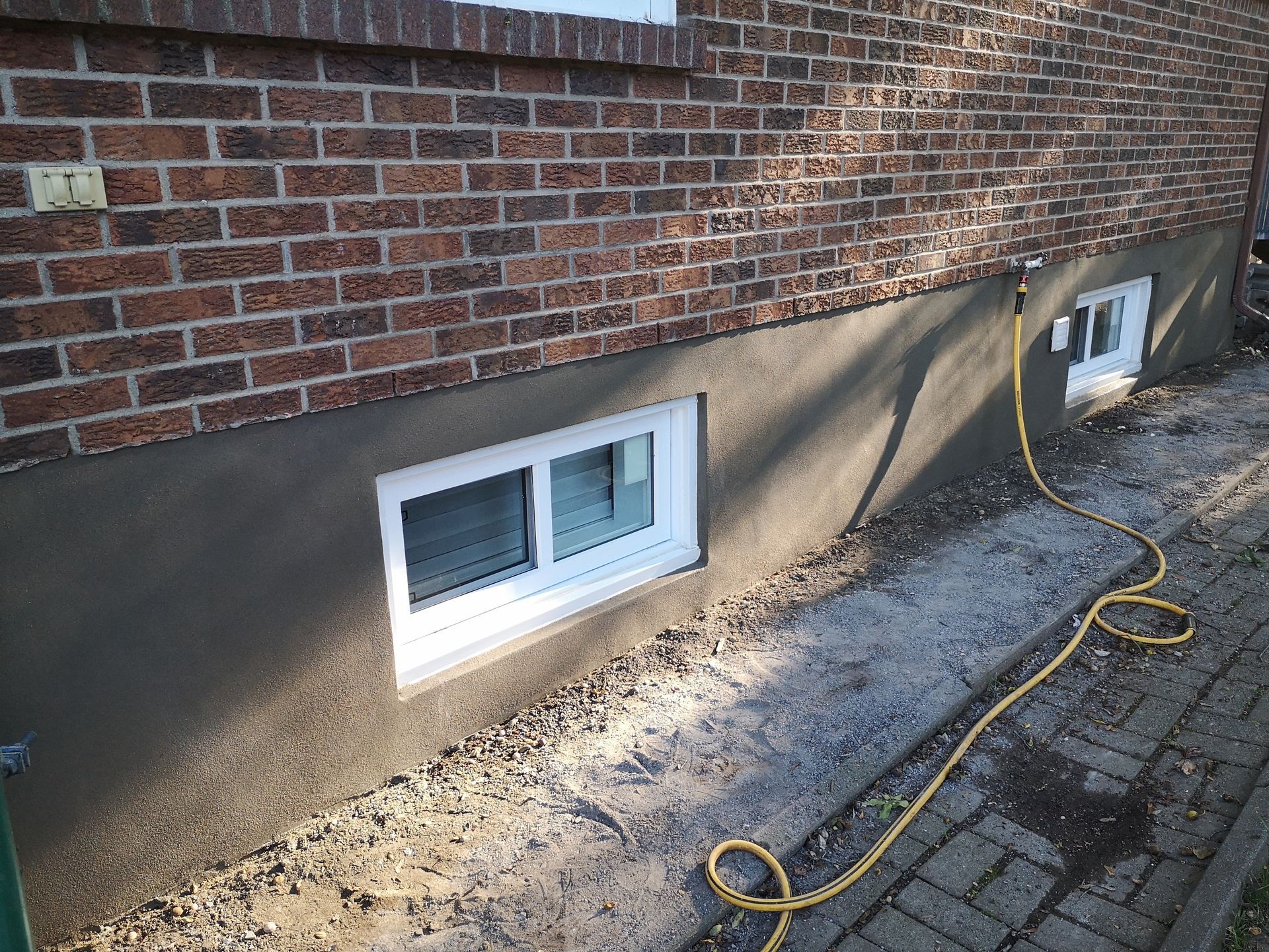 A hose is attached to the side of a brick building.