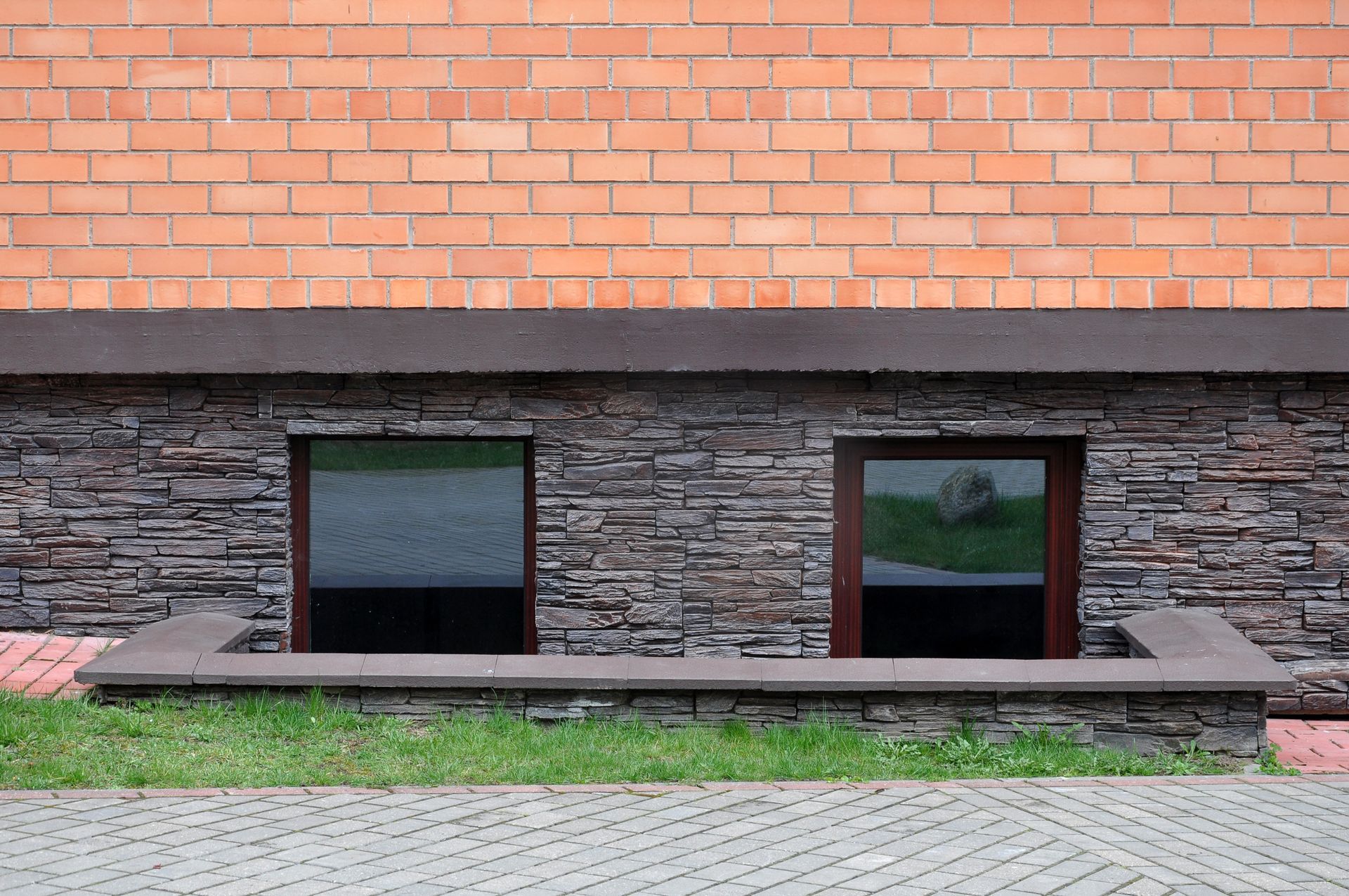 There are two windows on the side of a brick building.