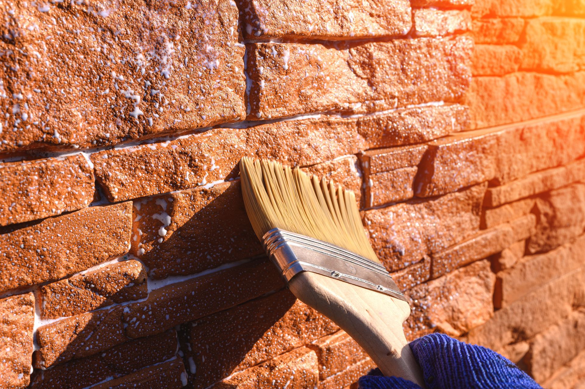 A person is painting a brick wall with a brush.