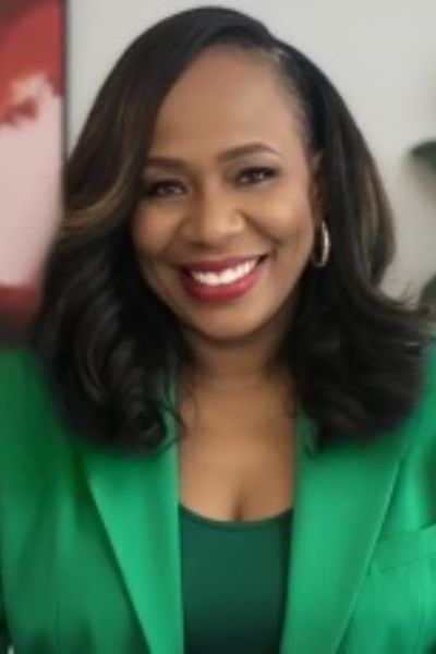 A professional headshot of author ReShonda Tate. She is a Black woman with shoulder-length, dark hair, smiling warmly at the camera. She is wearing a bright red top and subtle jewelry. The background is a soft, warm-toned indoor setting that puts the focus entirely on her.