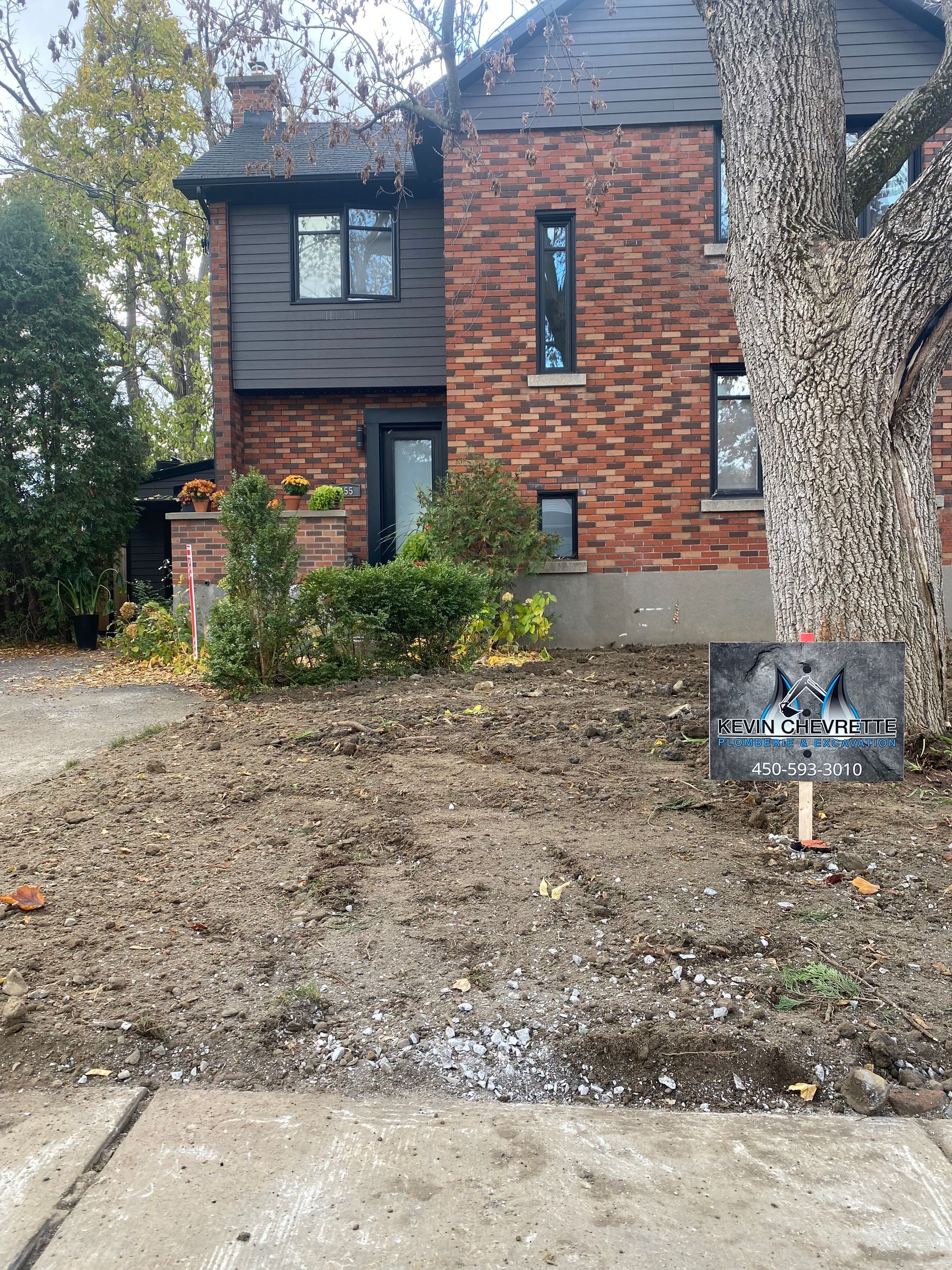Une maison en brique avec une pancarte devant.