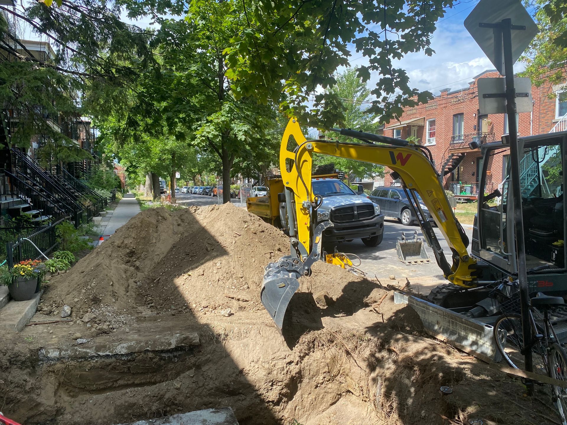 Une excavatrice jaune creuse un trou dans le sol.