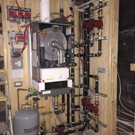 Une chaudière se trouve dans une pièce entourée de tuyaux et de fils.